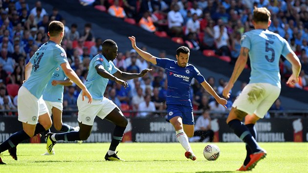Pedro z Chelsea (uprostřed v tmavě modré) kope do míče mezi třemi hráči Manchesteru City.