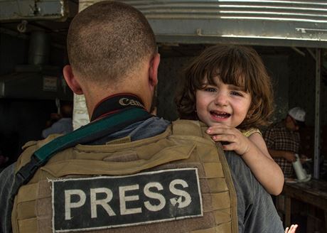 Válený reportér drící dít v dobyté tvrti msta Mosul.