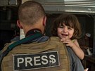 Válený reportér drící dít v dobyté tvrti msta Mosul.