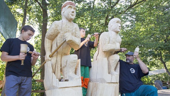 Známý řezbář Jiří Halouzka a jeho dva synové, třináctiletý René (vlevo) a o dva roky mladší Erik vyřezávají na vodáckém tábořišti v Horce nad Moravou na Olomoucku sochy dvou postav klečících v kánoi.