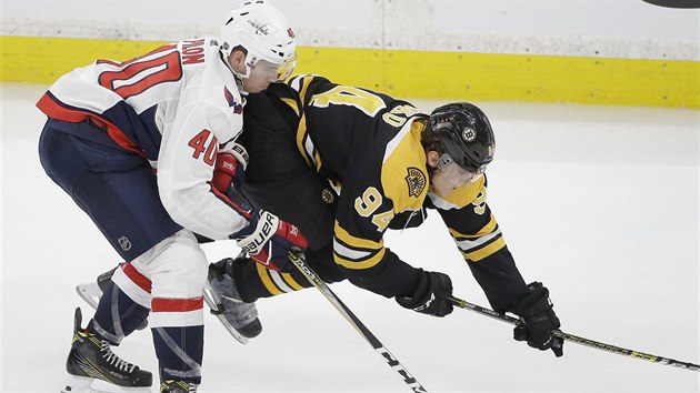 Český hokejista ve službách Bostonu Jakub Lauko (vpravo) padá na led v přípravném utkání po střetu s Garrettem Pilonem z Washingtonu.