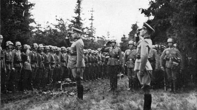 Momentka z nástupu jednotky na lesní mýtině před překročením čs. hranic. Nejblíže fotografovi salutují vlevo Generalleutnant Fahrmbacher a vpravo Oberstleutnant i. G. Gittner, autor knihy. (převzato z knihy Über den Böhmerwald ins Sudetenland).