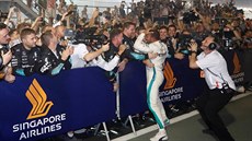 Lewis Hamilton slaví vítězství ve Velké ceně Singapuru v objetí týmových kolegů.