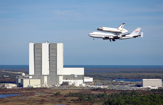 Raketoplán Columbia na hřbetě nosiče N905NA nad halou Vehicle Assembly Building...
