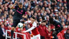 Mesut Özil z Arsenalu padá, atakují ho hrái Evertonu Richarlison (vlevo) a...