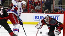 Branká Petr Mrázek z Caroliny elí anci Kevina Hayese z New York Rangers.