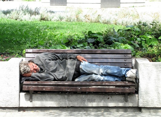 Bezdomovec leí na lavice v Budapeti.