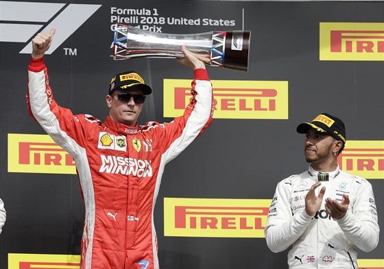 Kimi Räikkönen zvedá trofej pro vítze Velké ceny USA. Tleská mu Lewis Hamilton.