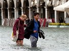 A couple walk on a catwalk in a flooded Saint Mark Square during a period of...