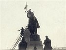 Lidé upevňují českou vlajku na kopí sochy sv. Václava na Václavském náměstí....