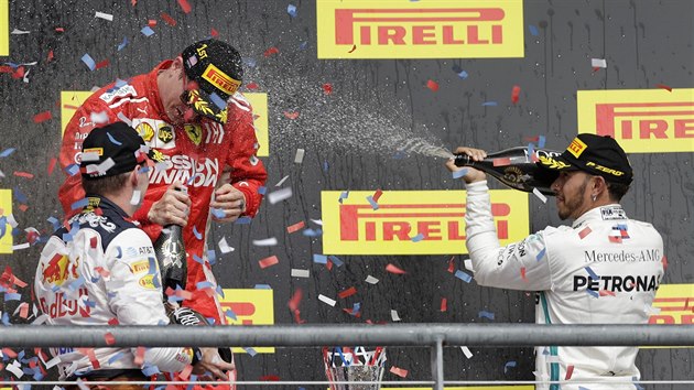 Vtz Velk ceny USA Kimi Rikknen (v ervenm) se kryje ped sprchou ze ampaskho, kterou mu dopv Lewis Hamilton.