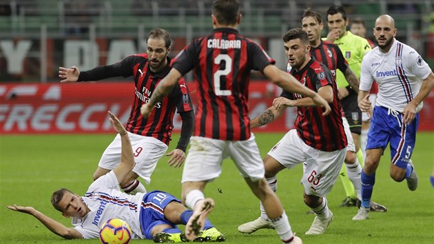 Dennis Praet ze Sampdorie (v bílém) spadl na trávník pod náporem přesily protihráčů z AC Milán.