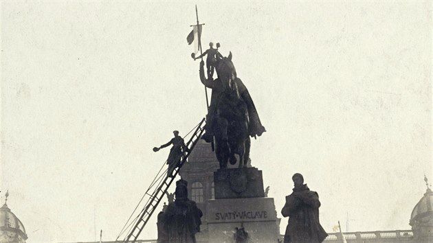Lidé upevňují českou vlajku na kopí sochy sv. Václava na Václavském náměstí. (28. října 1918)