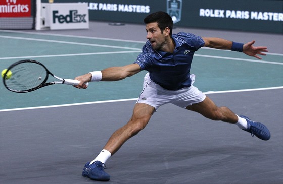 Srb Novak Djokovi se ve finále turnaje v Paíi snaí v krkolomné pozici...