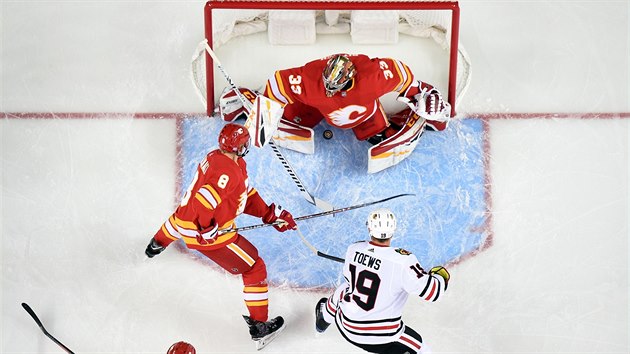 Brank Calgary David Rittich v ohroen, za glem se hrne Jonathan Toews z Chicaga.