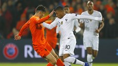 Francouz Kylian Mbappe (vpravo) v souboji s ,  Martenem de Roonem z Nizozemska.