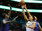 Malcolm Brogdon (v bílém) z Milwaukee zakonuje na ko Charlotte mezi Nicolasem...