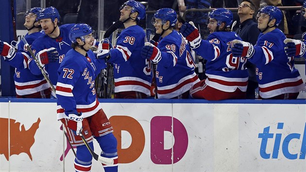 Filip Chytil z New York Rangers se raduje se spoluhráči na střídačce z gólu v derby s New York Islanders.