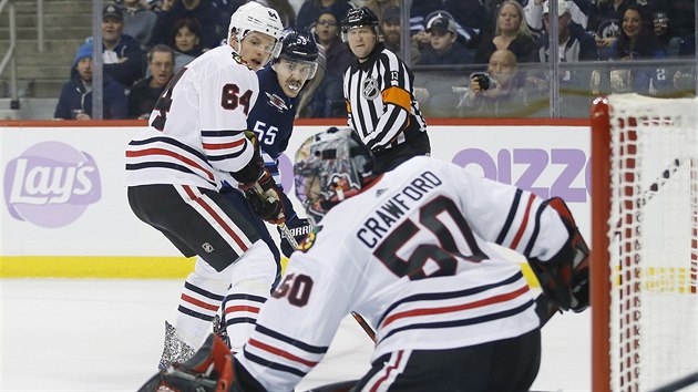 Mark Scheifele z Winnipegu, kterho brn David Kmpf z Chicaga, sleduje, jestli jeho stela propadne za branke Coreyho Crawforda.