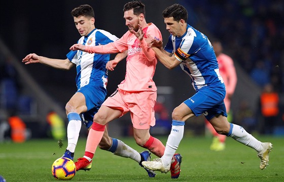 Lionel Messi prochází s míem mezi bránícími hrái Espanyolu.