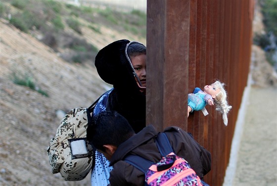 Migranti překonávají hraniční plot na americko-mexické hranici. (27. prosince...