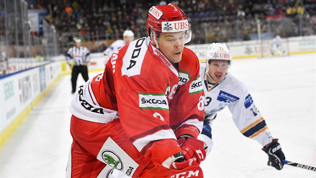 Aron Chmielewski (vlevo) odehrává puk v utkání Spengler Cupu, brání ho Roman...