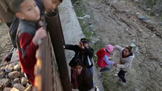 Migranti překonávají hraniční plot na americko-mexické hranici. (27. prosince...