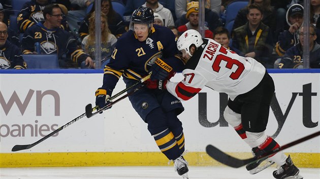 Kyle Okposo z Buffala se pokou uvolnit, brn ho Pavel Zacha z New Jersey.