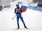 Rus Alexandr Loginov dojídí s vlajkou do cíle muské tafety v Oberhofu.
