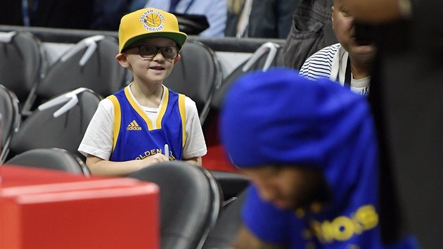 Malý fanoušek Golden State Warriors sleduje lelkujícího DeMarcuse Cousinse před tréninkem na zápas s Los Angeles Clippers.