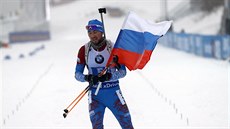 Rus Alexandr Loginov dojídí s vlajkou do cíle muské tafety v Oberhofu.