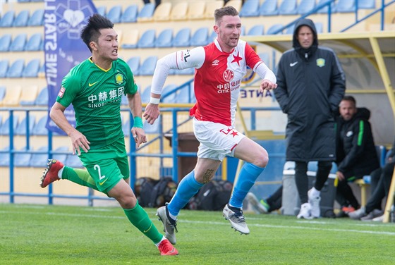 Jaromír Zmrhal (vpravo) ze Slavie utíká soupei z ínského týmu Peking Guoan.