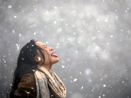 SNĚŽÍ. Žena chytá sněhové vločky na jazyk během sněžení v oblasti Chandragiri...