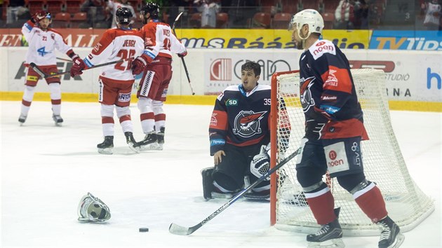 Odmaskovaný brankář Chomutova Dominik Pavlát nevěřícně reaguje na gól olomouckých hokejistů, kteří už společně slaví.