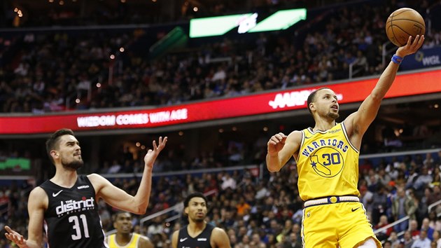 Tom Satoransk (vlevo) z Washingtonu sleduje, jak skruje Stephen Curry z Golden State.