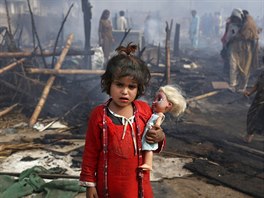 POÁR. Dívka stojí u spálenit, které zstalo po jejím domov ve slumu po...