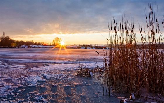 Slunce zapadající nad stále ještě zamrzlým jezerem Chomoutov na Olomoucku. (4....