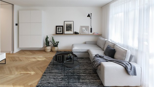 Byt má tři důležité prvky: jednotnou dřevěnou podlahu, bílou barvu a černé detaily.