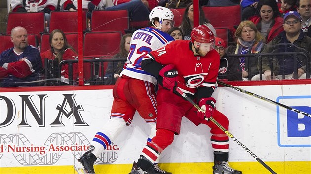 Filip Chytil z NY Rangers (vlevo) a Jaccob Slavin z Caroliny v souboji u mantinelu