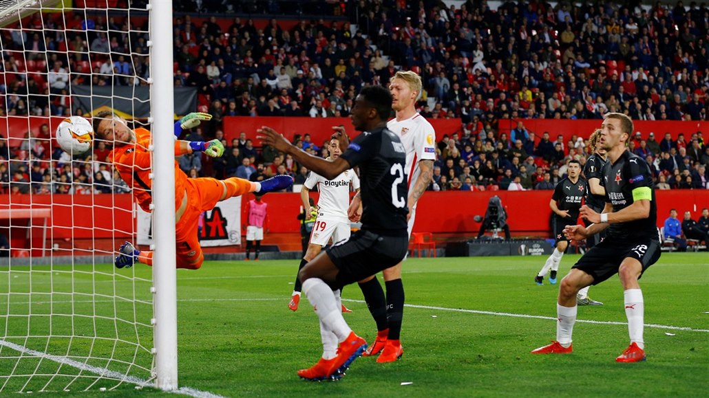 �eský branká� Tomá� Vaclík z FC Sevilla se marn� natahuje po mí�i, který se...