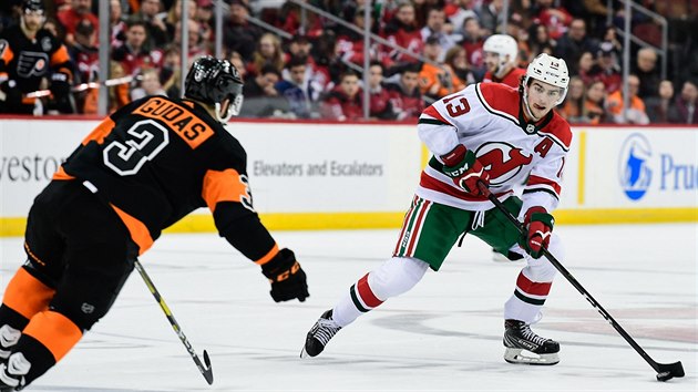 Nico Hischier z New Jersey s pukem na hokejce, proti nmu startuje Radko Gudas z Philadelphie.