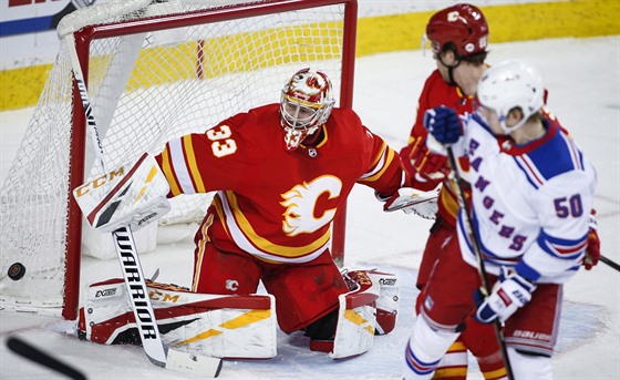 Lias Andersson z New York Rangers sleduje zákrok brankáe Calgary Davida...