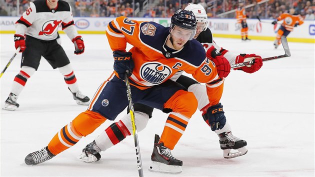 Connor McDavid z Edmontonu si kryje puk, brn ho Andy Greene z New Jersey.