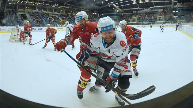 Ivan Huml z Chomutova (v blm) a Tom Rolinek z Pardubic bojuj u mantinelu bhem zpasu tvrtho kola play out hokejov extraligy.