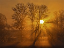 SVÍTÁNÍ V MLZE. Slunce stoupá nad obzor v mlze u města Lebus na hranicích...
