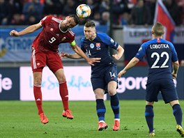 Maarsk fotbalista Adam Szalai hlavikuje ped slovenskm reprezentantem...