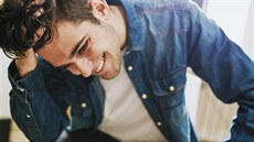 fashionable young man smiling with his hand on his hair, portraits