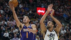 Devin Booker (1) z Phoenixu donáí mí do koe Utahu kolem Rudyho Goberta.