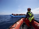 Migranti na gumovém lunu jsou osloveni pracovníky záchranných lodí Sea-Watch...