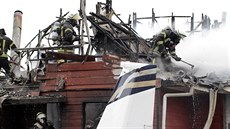Záchranái likvidují ohe, který zpsobil náraz letadla do obytného domu v...
